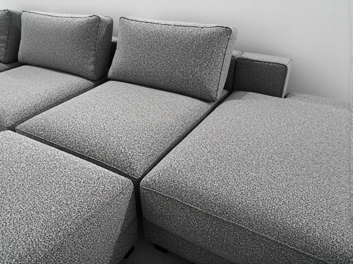 Kompaktowy narożnik w kształcie litery L ustawiony pod oknem, oszczędzający miejsce w małym mieszkaniu.